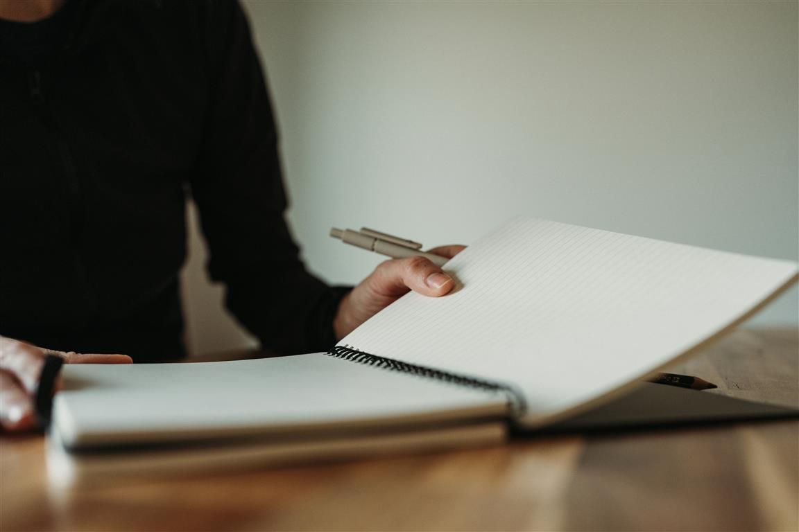 A woman sitting at a table taking notes in a notebook
