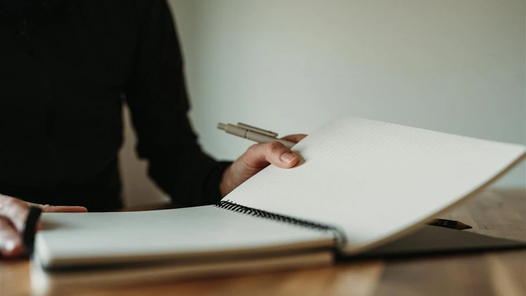 A woman sitting at a table taking notes in a notebook